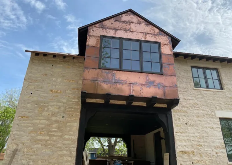 Copper metal panel facade on a stone building for Roof Repair in Moraine