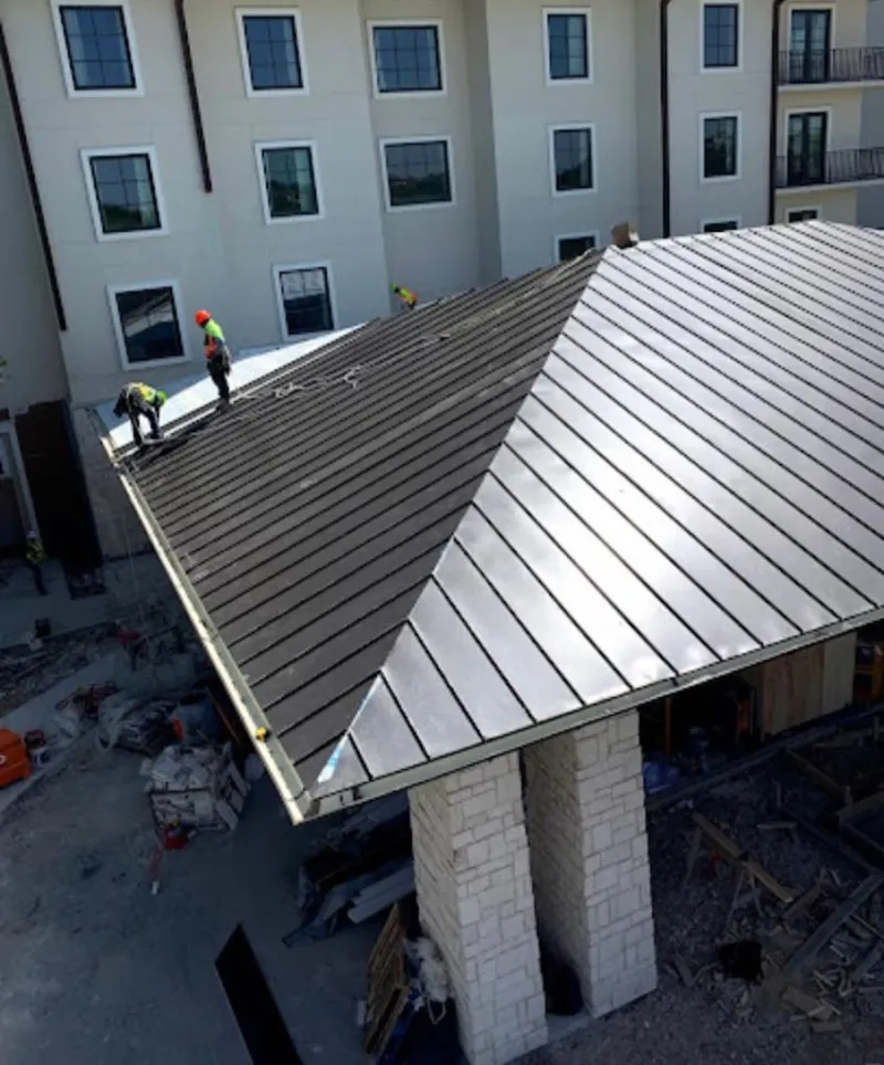 Crew installing standing seam metal roof panels on a commercial project in Moraine